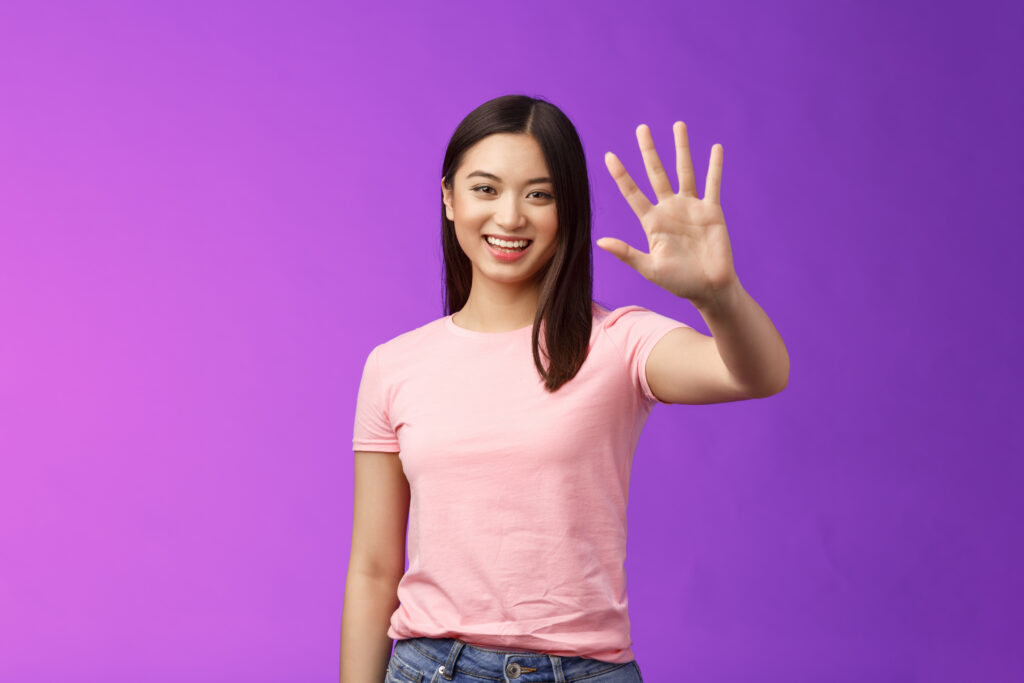 asain woman holding up five fingers and smiling against a purple background, representing 5 reasons to go to outpatient substance use treatment