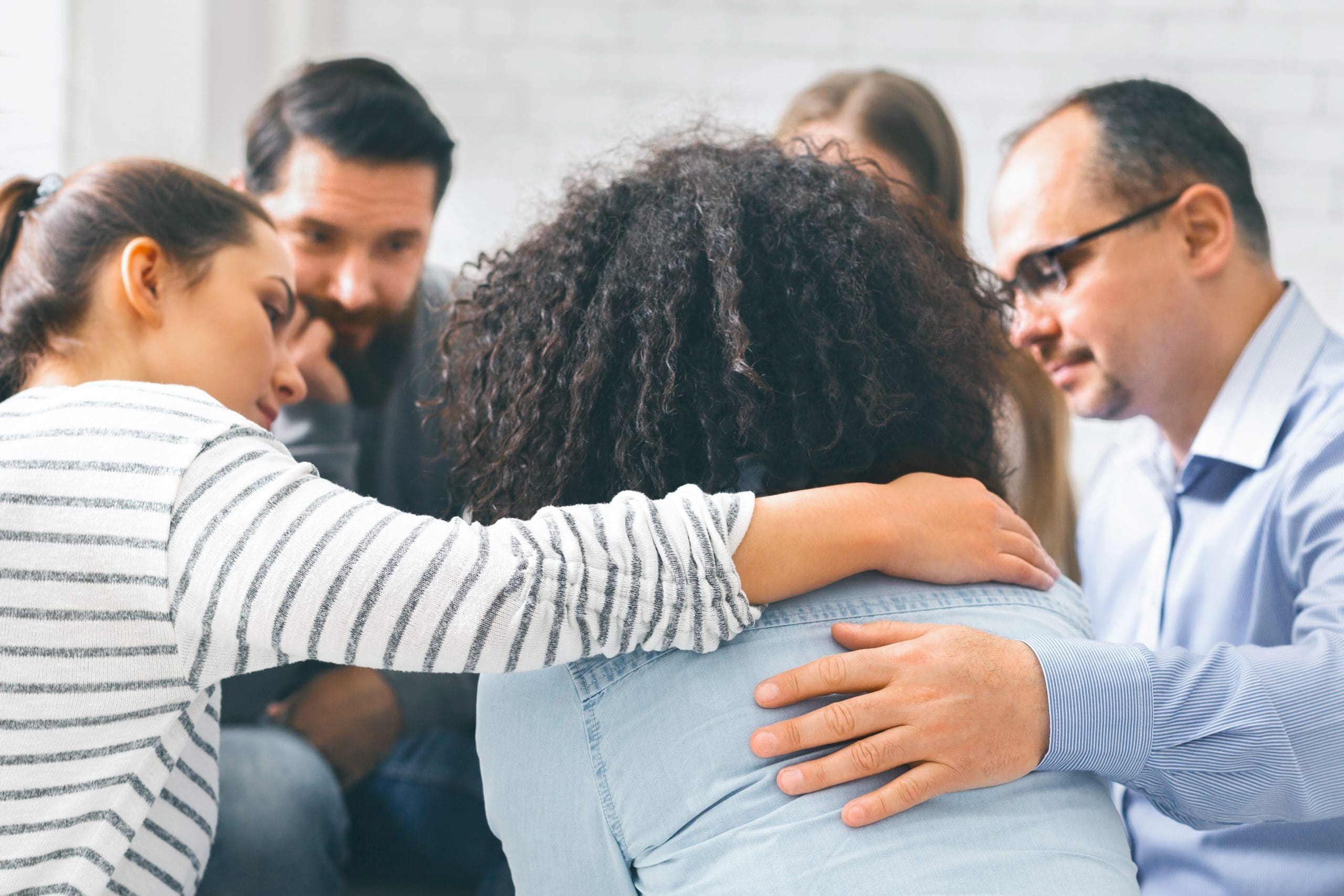 people comforting a woman at a support group for spouses of alcoholics