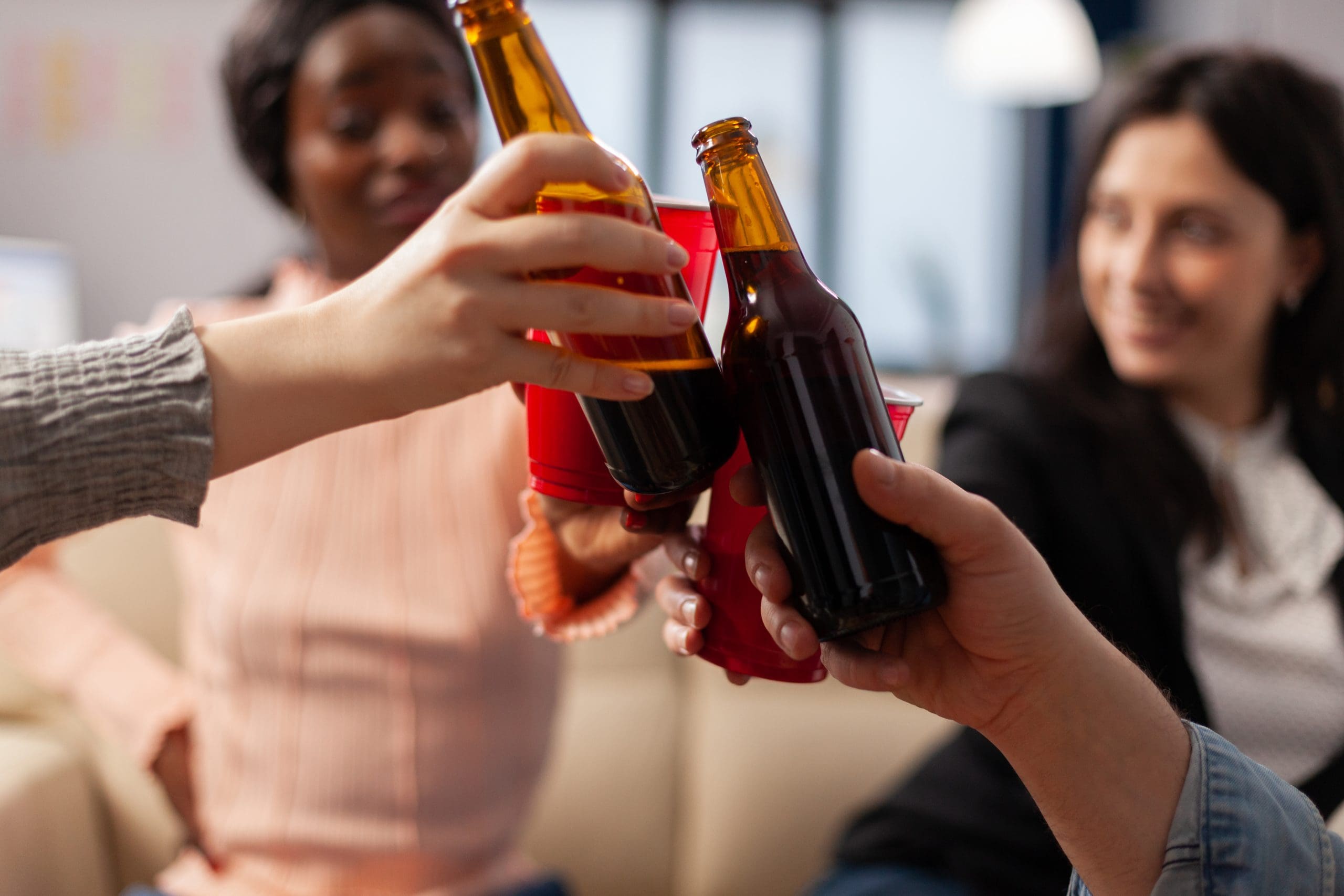 close up of teens holding bottles and red solo cups as peer pressure is a factor that can potentially increase a teenagers alcohol use