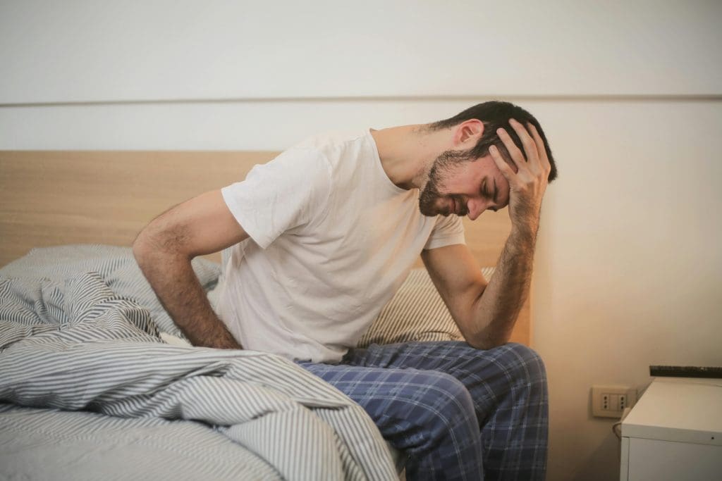 a man battling insomnia on the edge of his bed because of his addiction to pentothal.