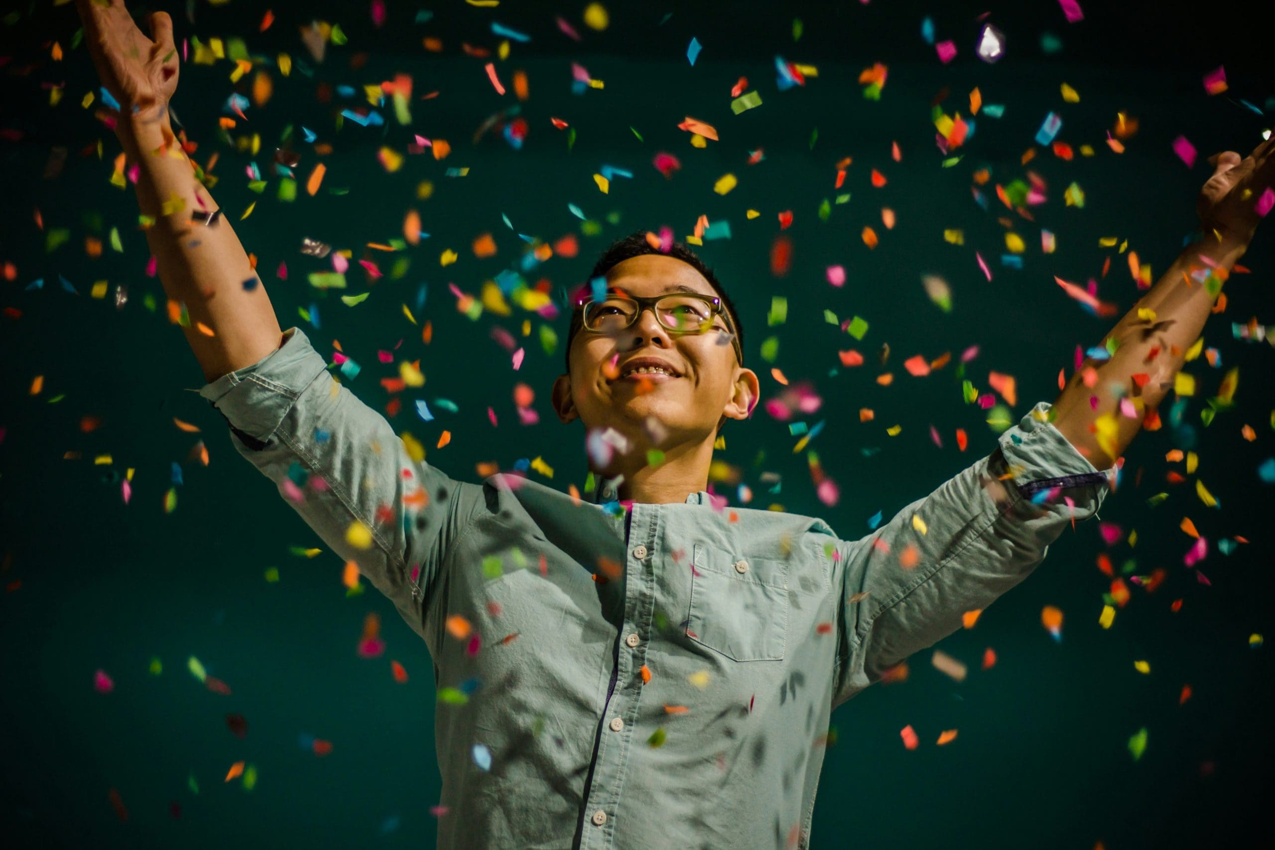 A woman celebrating sobriety progress by throwing confetti in the air.
