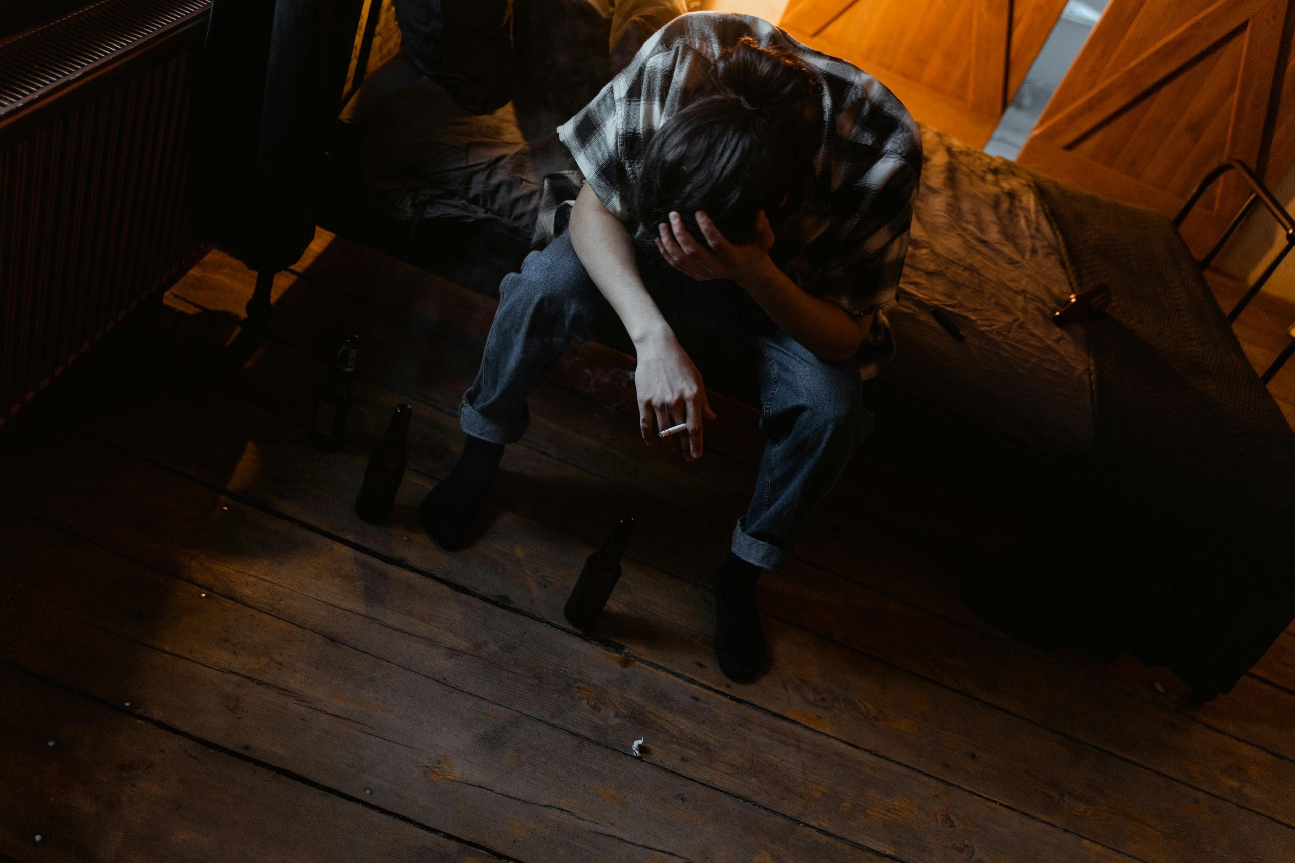 A man sitting at the edge of his bed struggling to manage withdrawal symptoms.