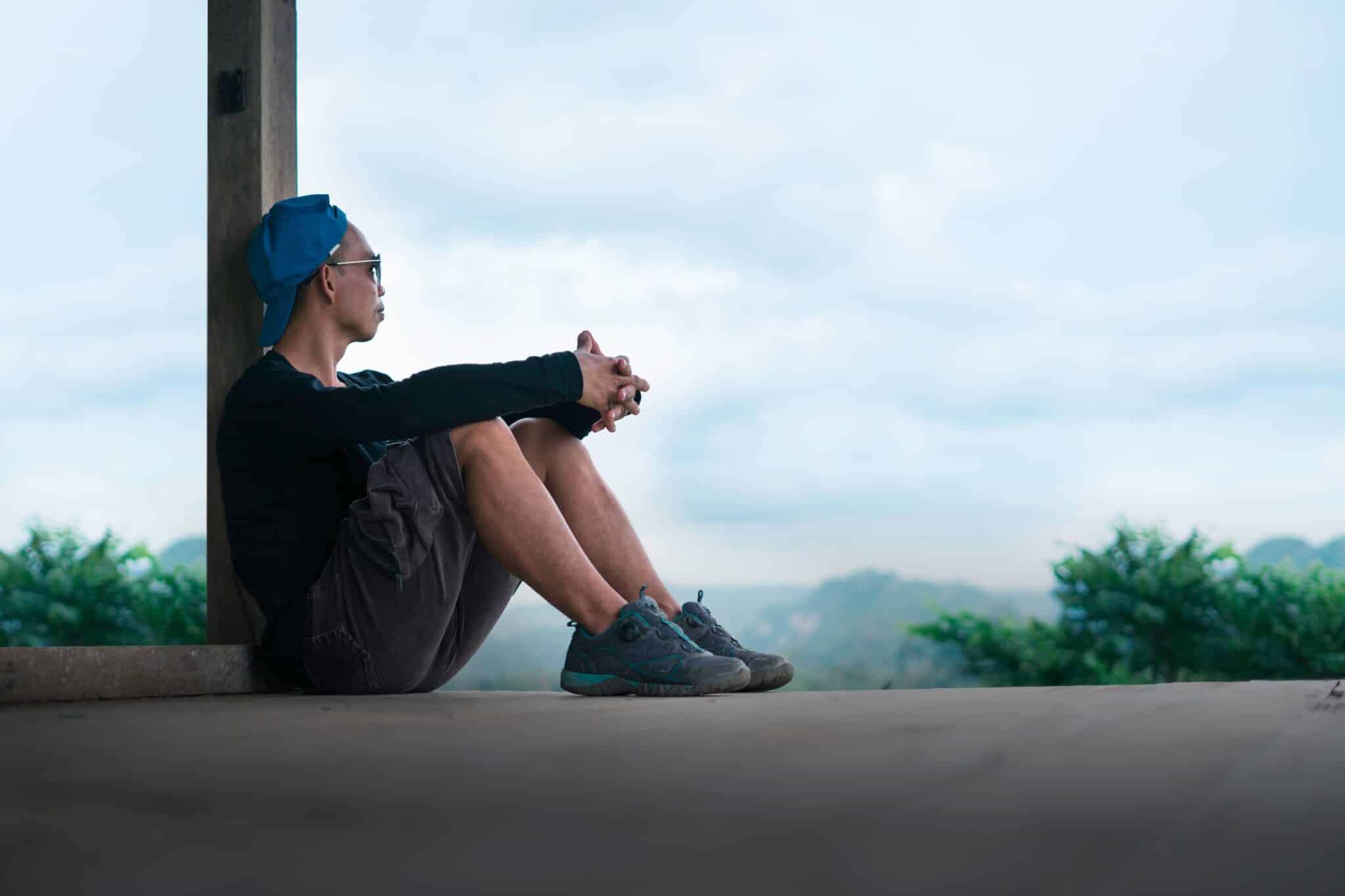 Person sitting on a porch step with hands loosely clasped, reflecting quietly